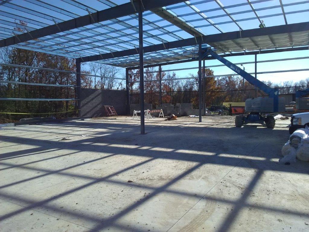 A large building under construction, featuring prominent steel beams and a crane positioned nearby