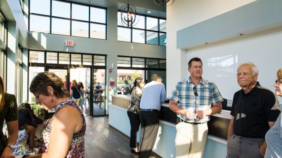 People are positioned in a lobby, where a large window allows ample natural light to fill the space
