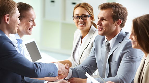 Business professionals engaging in a handshake within a modern office setting, symbolizing partnership and collaboration